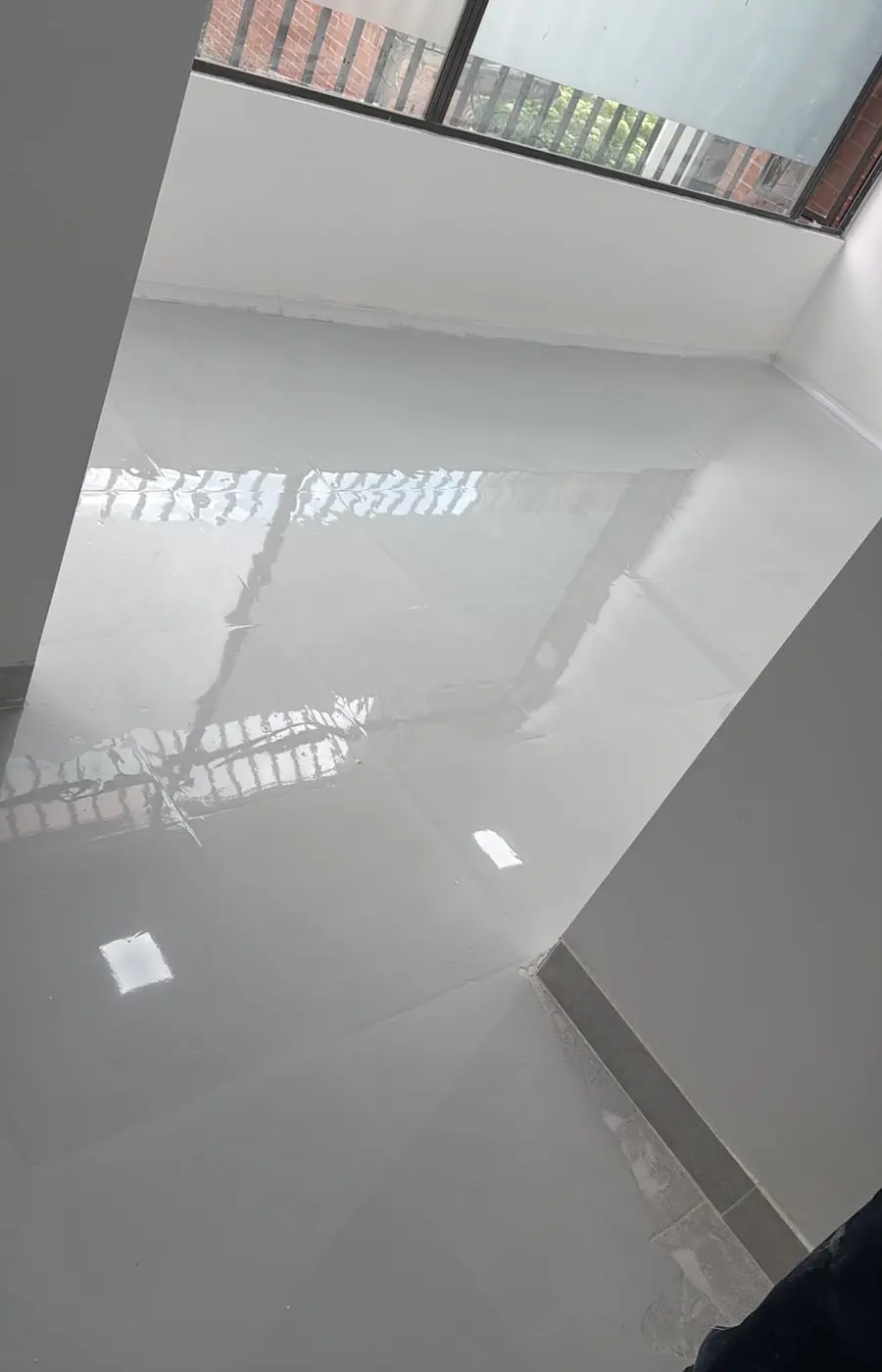 Piso epóxico blanco de alto brillo en el que se refleja una ventana