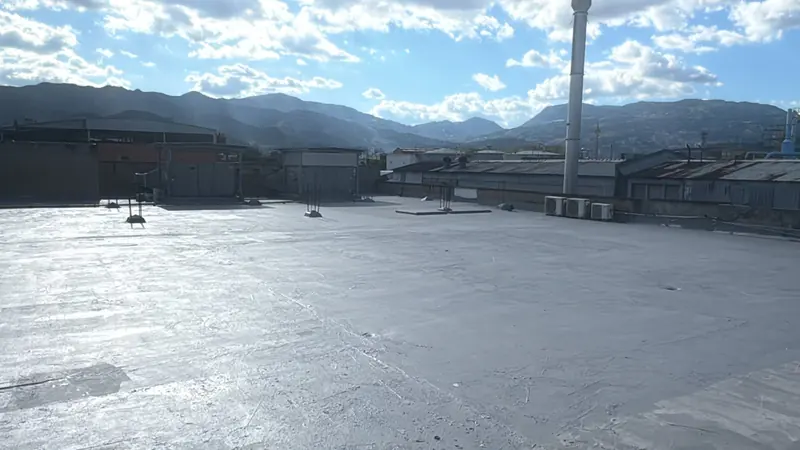 Cubierta industrial amplia recubierta en gris con montañas al fondo