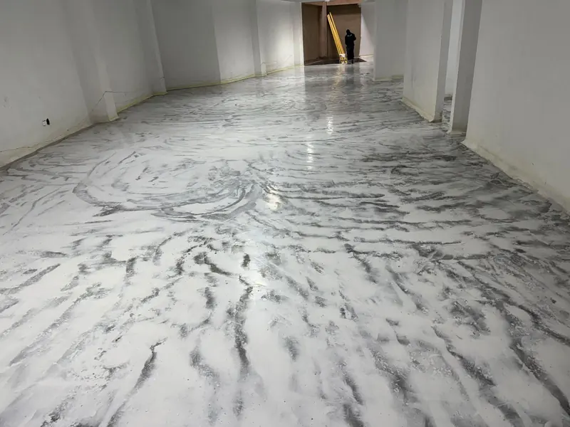 Piso epóxico blanco con vetas grises que imitan mármol en un local alargado