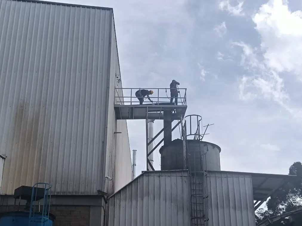 Dos operarios trabajan sobre la plataforma de un tanque industrial