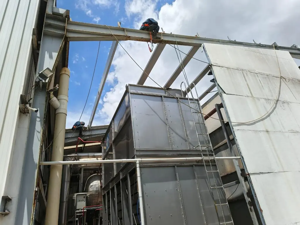 Operarios trabajan en altura sobre la estructura metálica de una cubierta industrial