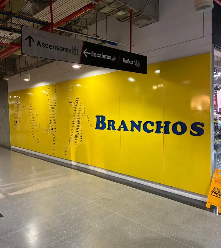 Pared de lámina amarilla microperforada con figuras de deportistas en un local comercial